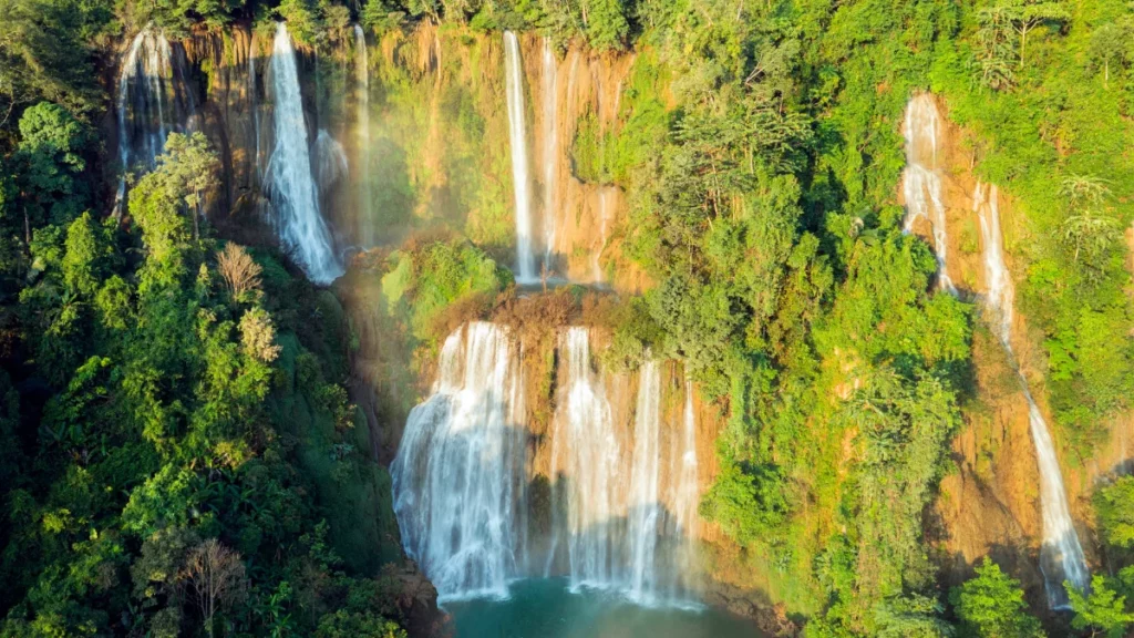 Cascade de Thi Lo Su s’écoulant sur plusieurs paliers rocheux vers un bassin bleu clair, entourée d’une végétation dense.