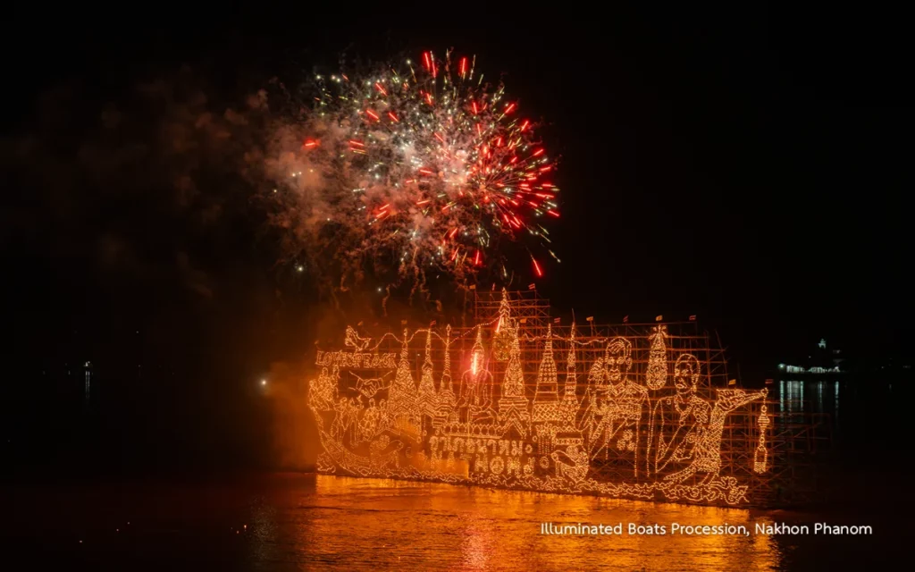 Een enorme boot, versierd met duizenden lichtjes, vaart over de Mekong onder rood en goudkleurig vuurwerk tijdens het Lai Reua Fai-festival in Nakhon Phanom.