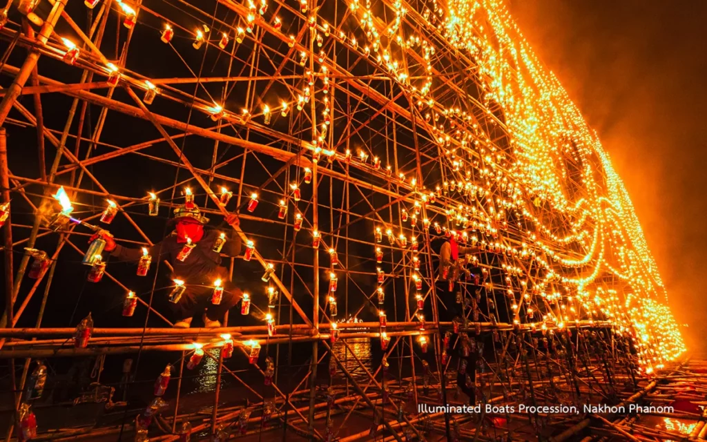 Deelnemers bevestigen en ontsteken lichtjes op een indrukwekkende bamboeconstructie ter voorbereiding op de verlichte botenprocessie in Nakhon Phanom.