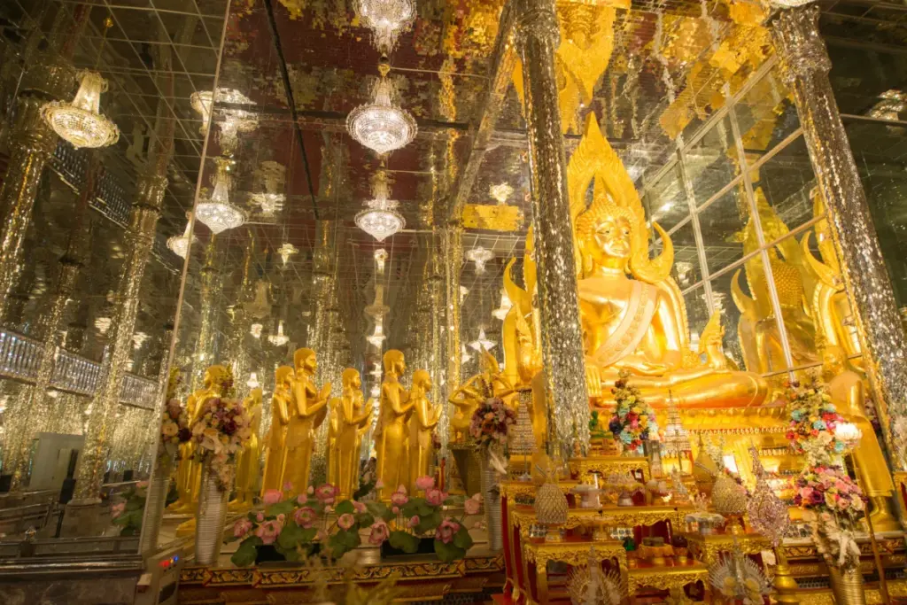 Groot gouden Boeddhabeeld in de spiegelzaal van Wat Tha Sung, omringd door schitterende zuilen.
