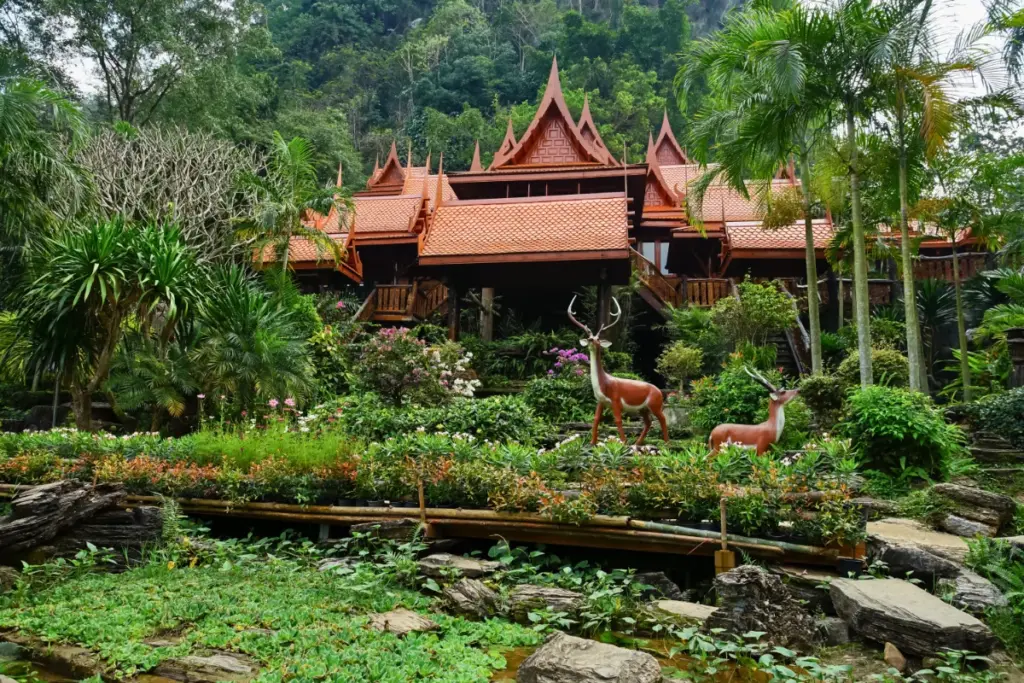 Houten gevel van Wat Tham Khao Wong, met tropische bloemen, palmbomen en beelden van herten.